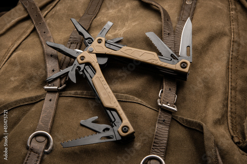 Modern multitool with many tools. A portable multitasking tool on a vintage canvas backpack. photo