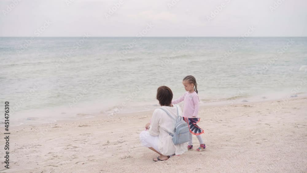 Mother With Little Child Blowing Soap Bubbles On Sea Beach Traveling with one Children Family Summer Vacation. Mom And Little Girl Playing Outdoors Mother With Little Child Blowing Soap Bubbles On Sea Beach Traveling with one Children Family Summer Vacation. Mom And Little Girl Playing Outdoors