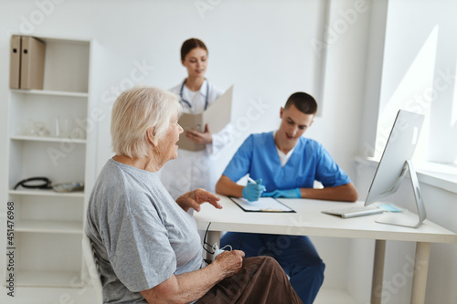 an elderly woman sitting at a doctor's appointment with a nurse treatment diagnostics