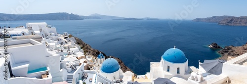 Panoramic view of Oia town in Santorini island with old whitewashed houses and traditional blue dome churches, Greece Greek landscape on a sunny day
