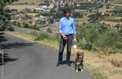 Tall italian man walking dog against the backdrop of a tuscan landscape 