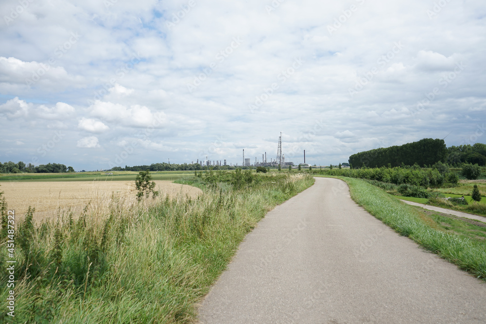 road in the countryside with industrial complex in background road in the countryside with industrial complex in background