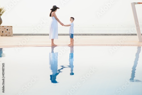 Young mother and son walking near swimming pool. Summer vacation concept