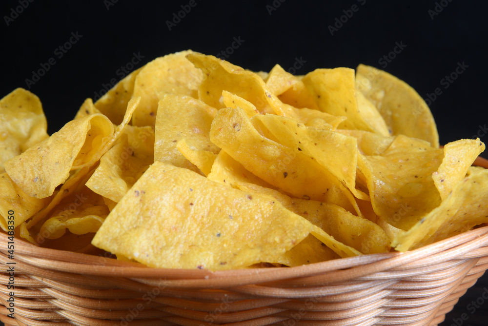 delicious mexican corn nachos inside reed canister isolated on black background.
