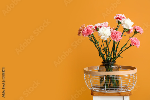 Fototapeta Naklejka Na Ścianę i Meble -  Vase with carnation flowers on table near color wall