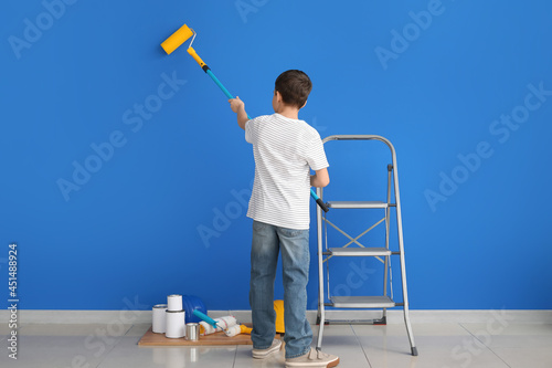 Little boy painting wall in...