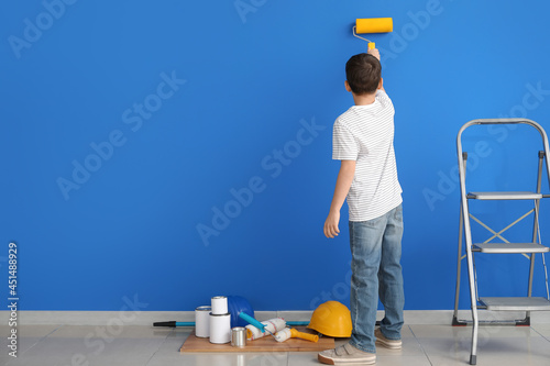 Little boy painting wall in...