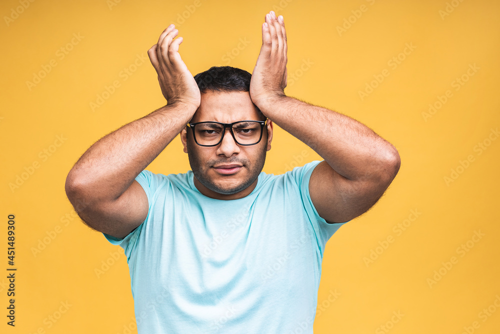 Portrait of sad updet or bored african american black indian young man standing and looking at camera with dissatisfied sadness face. Indoor studio shot, isolated on yellow background. Portrait of sad updet or bored african american black indian young man standing and looking at camera with dissatisfied sadness face. Indoor studio shot, isolated on yellow background.