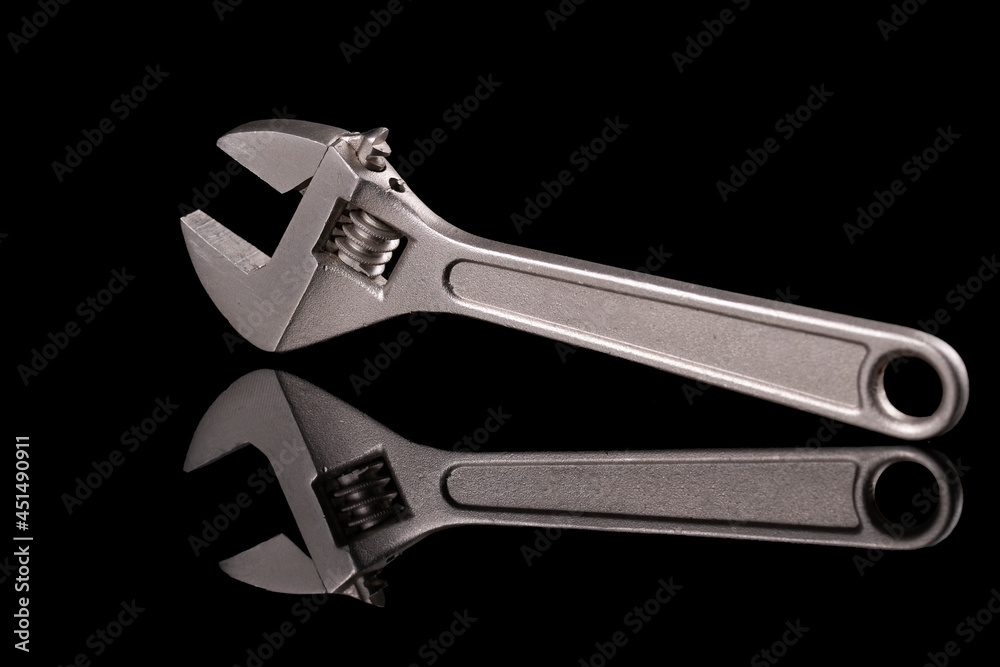 An adjustable wrench on a shiny dark base. Tools used in a mechanical workshop.