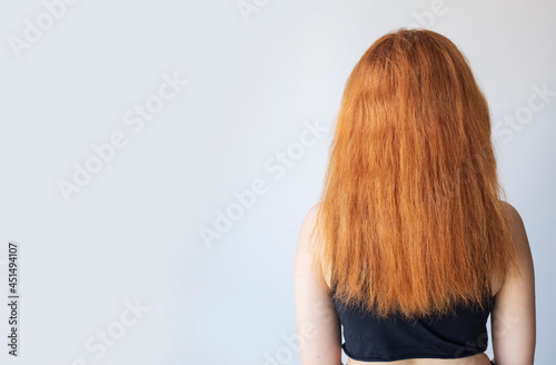 Back view of upset woman with dry damaged hair problem with plain background. Copy space.