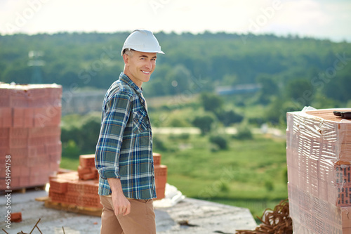 High-spirited middle-aged worker standing among the construction materials