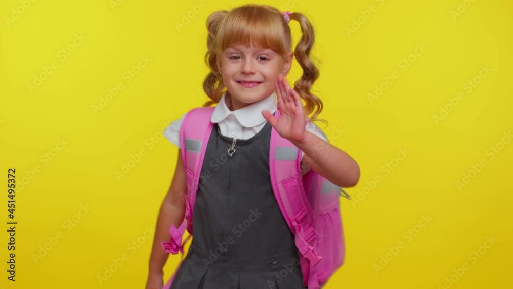 Cheerful blond teenage schoolgirl kid dressed in uniform waves hand palm in hello gesture welcomes someone with hospitable expression expresses positive emotions. Education, back to school, study Cheerful blond teenage schoolgirl kid dressed in uniform waves hand palm in hello gesture welcomes someone with hospitable expression expresses positive emotions. Education, back to school, study