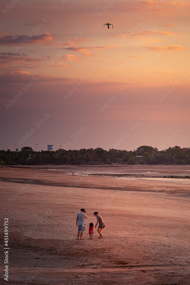 Family flying a kite at the beach at sunset in Darwin, Northern Territory, Australia