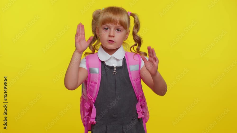 Kid primary school girl say no hold palm folded crossed hands in stop gesture, warning of finish, prohibited access, declining communication, body language, danger on yellow background. Back to school Kid primary school girl say no hold palm folded crossed hands in stop gesture, warning of finish, prohibited access, declining communication, body language, danger on yellow background. Back to school