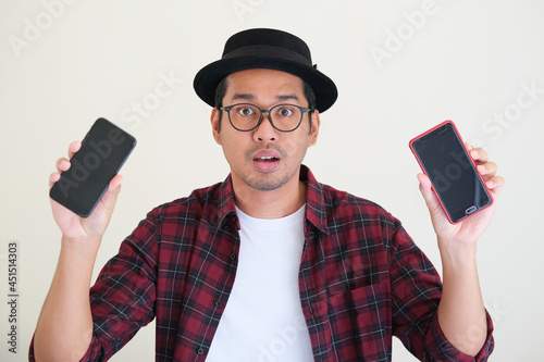 Asian man showing two different type of mobile phone for comparison photo