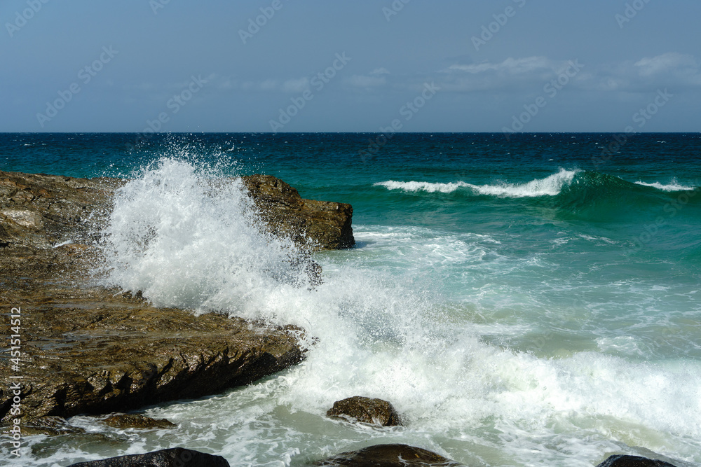 Surf wave crashing on rock that looks like a sleeping dog, at Coolangatta, Queensland, Australia. 