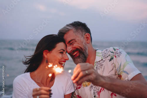 Couple celebrating with sparklers at the beach photo