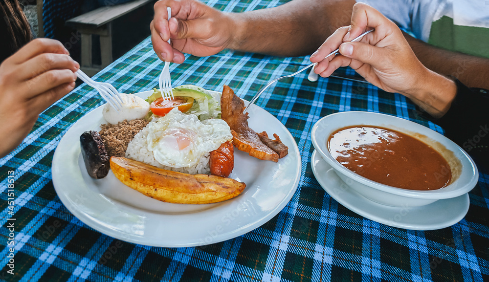 A group of people eat the typical Colombian food called Bandeja Paisa A group of people eat the typical Colombian food called Bandeja Paisa