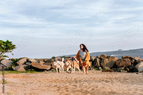 Photography one girl walking with two husky dogs at the beach