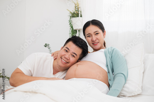 Asian couple, young pregnant woman with her husband, feeling happy in bedroom © Nattakorn