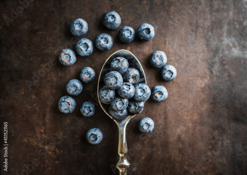 Blueberries on the spoon on rustic background. Shot from above. Selective focus.