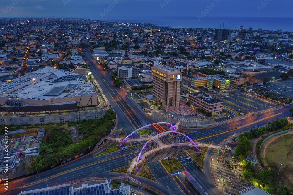 Landscape of a modern city surrounded by lights in the evening in the Dominican Republic - obrazy, fototapety, plakaty 
