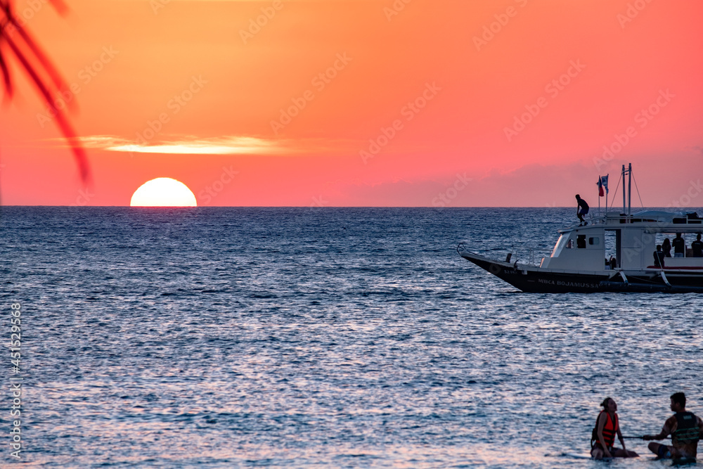 Naklejka premium Boracay, Philippines - Jan 21, 2020: Sunset on the background of bottles standing on the bar. The sun passes through the bright glass of the bottles. Background image for the screensaver.