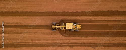 Aerial view yellow excavator building a highway, Road grader heavy earth moving, Bulldozer working at road construction.