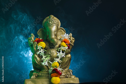 Golden lord ganesha sclupture over dark background. celebrate lord ganesha festival. photo