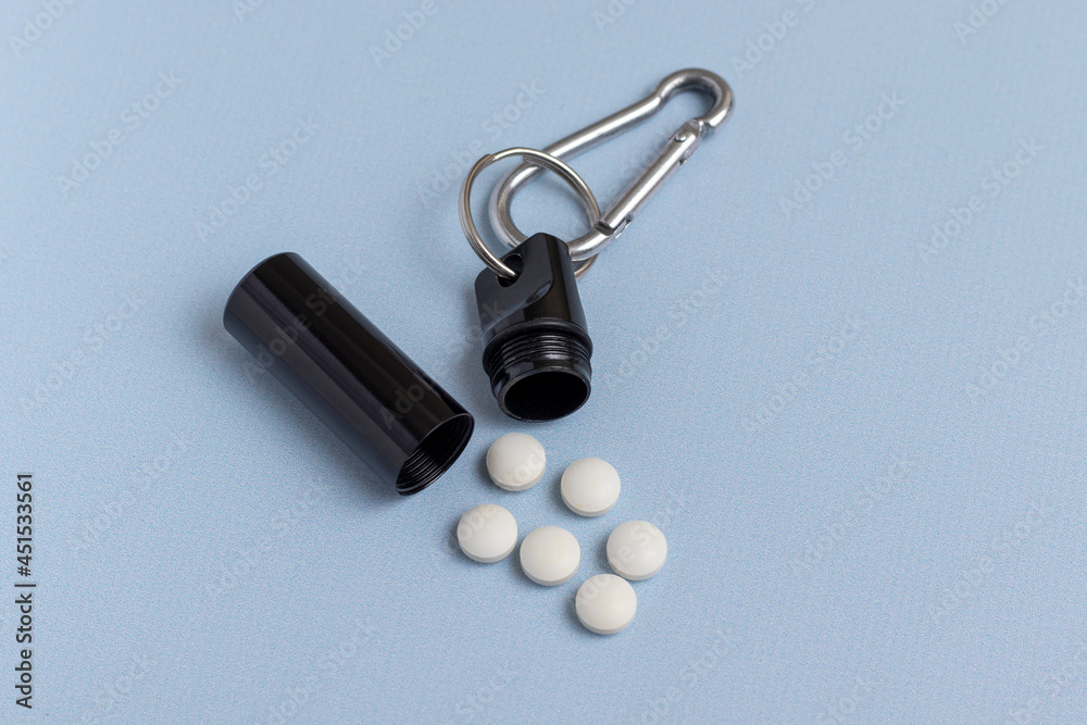 Naklejka premium Metal box for medicine and pills on blue background. Pill box connected with a carbine.