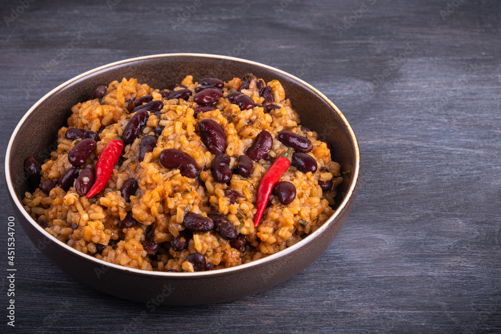 Portion of mexican tomato rice with beans in a plate on a dark background, copy space Portion of mexican tomato rice with beans in a plate on a dark background, copy space