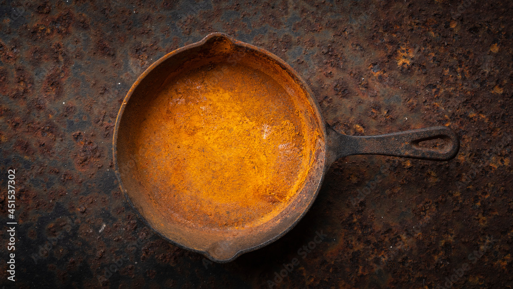 rusty cast iron skillet on a dirty rust metal plate texture background
