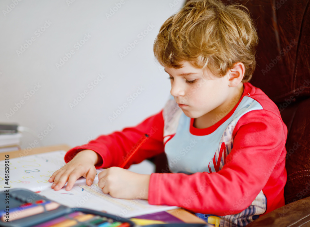 Portrait of cute happy school kid boy at home making homework. Little child writing with colorful pencils, indoors. Elementary school and education. Kid learning writing letters and numbers Portrait of cute happy school kid boy at home making homework. Little child writing with colorful pencils, indoors. Elementary school and education. Kid learning writing letters and numbers