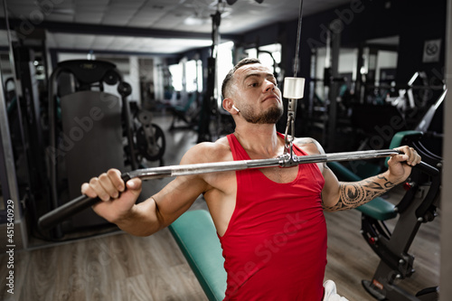 Portrait of man bodybuilder in red shirt in gym