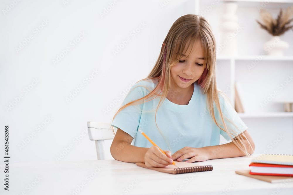 Teenage girl making notes in notepad, doing homework at table at home Teenage girl making notes in notepad, doing homework at table at home