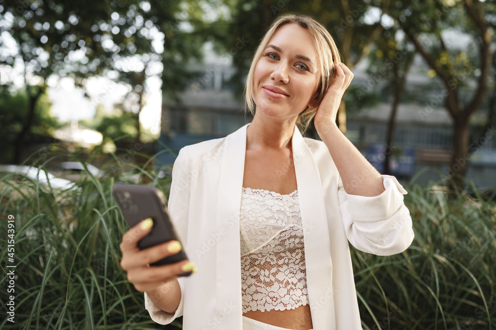 Beautiful young blonde businesswoman using smartphone in the city Beautiful young blonde businesswoman using smartphone in the city