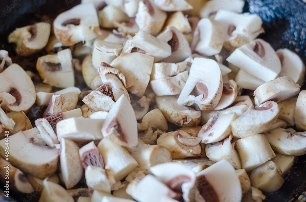 Close-up of raw mushrooms in a heated frying pan. Moisture evapo Close-up of raw mushrooms in a heated frying pan. Moisture evapo