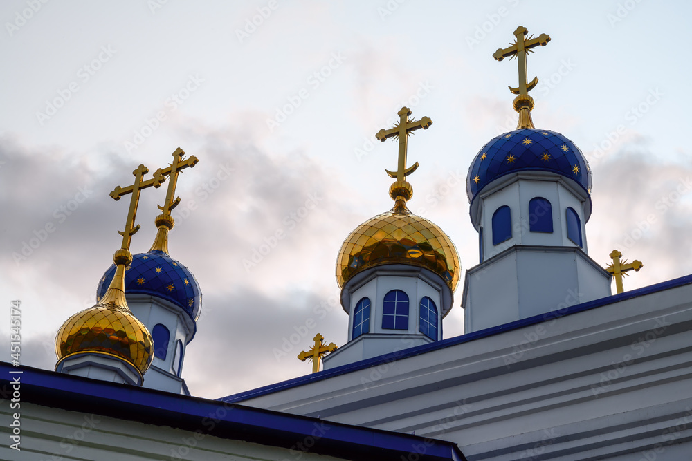 Blue domes with gold stars of the ancient Church of the Ascension in the village of Bolshie Brusyany (Ural, Russia). Close-up of a golden dome. White brick air church. The legacy of ancestors. 