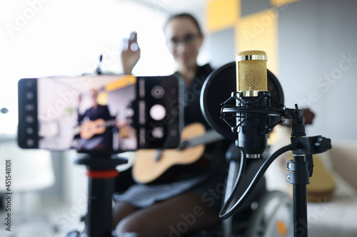 Woman in wheelchair is recording online guitar lesson