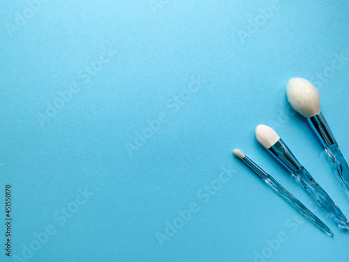 Brushes a flat lay with copy space. Beauty cosmetic makeup product layout. Stylish design. Creative fashionable concept. Cosmetics make-up brushes collection on a blue background, top view. 