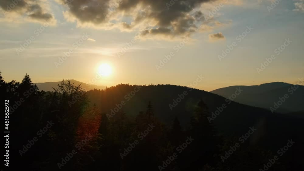 custom made wallpaper toronto digitalAerial view drone cinematic shot of mountains at calm orange sunset. Sun rays. Green pine forest slopes of mountain range. Bright disk of sun in blue sky slowly sets tops of mountains