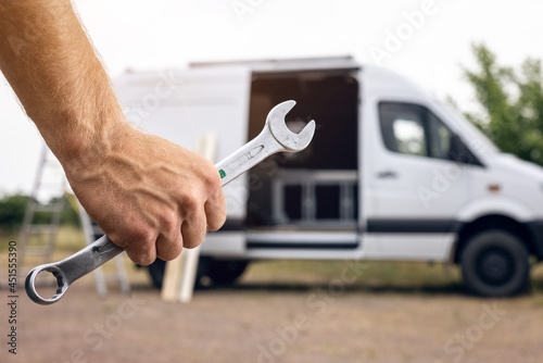 Wrench held by a hand with a van in the background