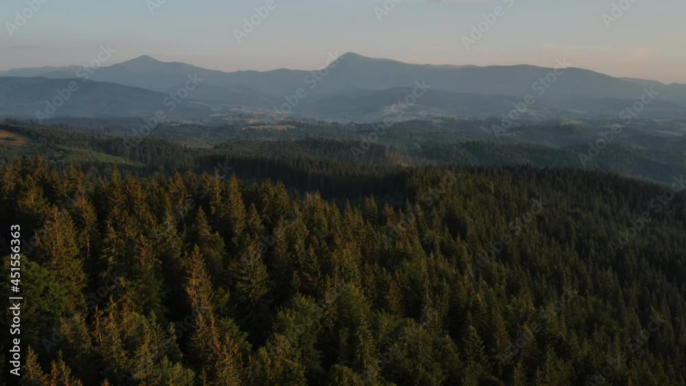 Incredible cinematic aerial shot of beautiful majestic mountains, summer green pine forest and blue sky during calm sunset or sunrise. Adventure and exploration of outdoors concept Incredible cinematic aerial shot of beautiful majestic mountains, summer green pine forest and blue sky during calm sunset or sunrise. Adventure and exploration of outdoors concept