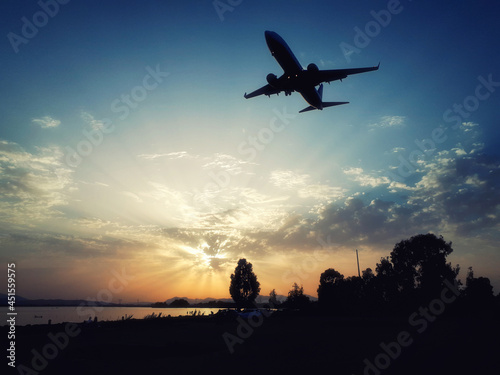 Spectacular landing during the sunset in the lagoon. Wonderful sunset with an airplane landing at low altitude. Aircraft silhouette.