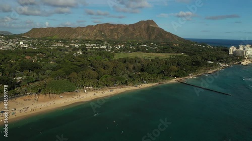 Aerial drone footage flying above Waikiki Beach on the island of Oahu, Hawaii, USA. Boats on water, hotels and people on the beach. Diamond Head volcano in the background. Late afternoon light. 