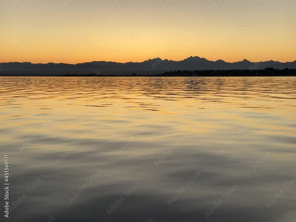 A bright orange dawn sky reflects on a calm Puget Sound outside of Everett with the silhouettes of the Cascade Mountains in the distance, making a gorgeous golden hour video. A bright orange dawn sky reflects on a calm Puget Sound outside of Everett with the silhouettes of the Cascade Mountains in the distance, making a gorgeous golden hour video.
