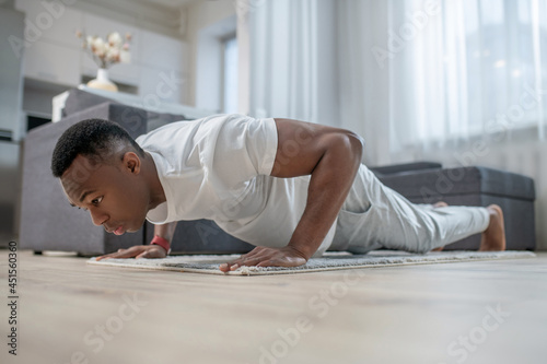 African american guy in white clothes doing morning exercises