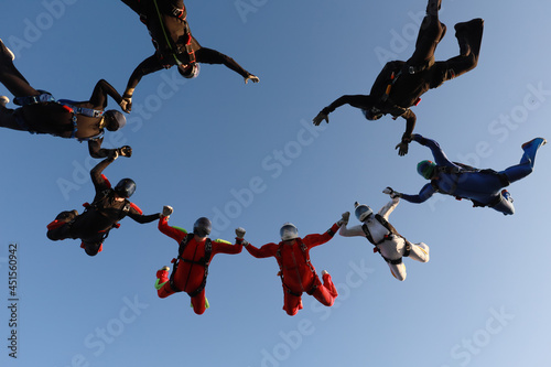 Skydiving.  A team of skydivers is in the sky.