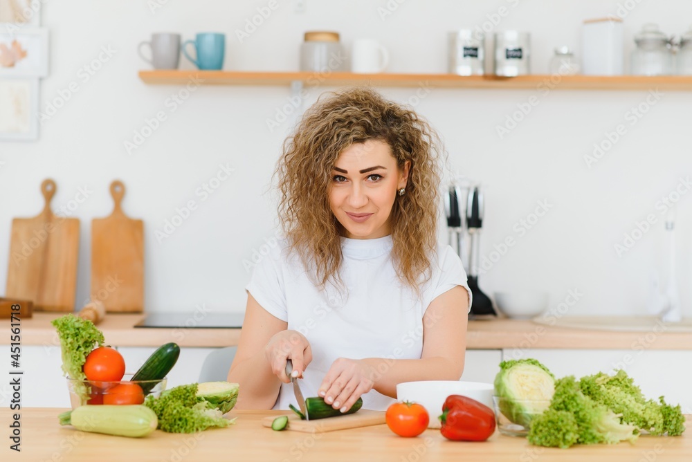 Happy young housewife mixing vegetable salad Happy young housewife mixing vegetable salad