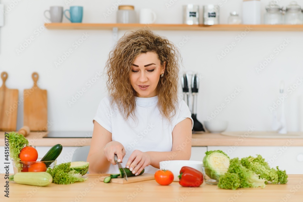 Happy young housewife mixing vegetable salad